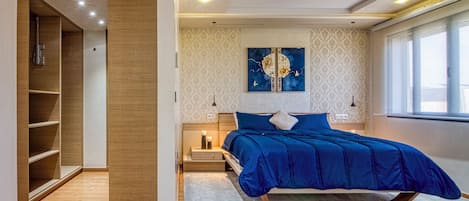A modern bedroom with a bed, bedside tables, a nightstand, a wardrobe, and a window with curtains.