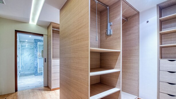 Een moderne badkamer met een glazen douchecabine, houten kastjes en een douchegedeelte betegeld met marmer.