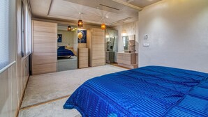 Een slaapkamer met een groot bed, een kledingkast, een dressoir en een spiegel.