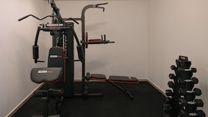 Una palestra con attrezzature fitness Hercules e Axxon, tra cui una panca, una panca per squat e manubri.