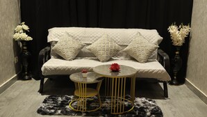 A modern living room with a sofa, two side tables, and decorative vases.