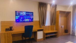 Een moderne kamer met een houten bureau, een blauwe stoel en een flatscreen-tv waarop een interface voor een thuiskantoor te zien is.