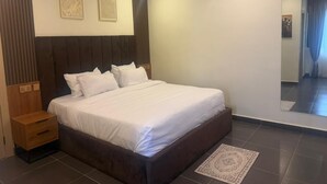 Een moderne slaapkamer met een groot bed, een nachtkastje en een spiegel.