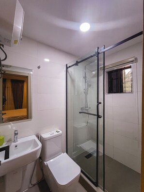 A bathroom with a glass-enclosed shower, a sink, and a toilet. - C & C Luxury Suites (Lagos)