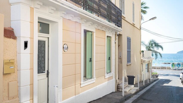 A building with a balcony, a door, and a window with shutters.