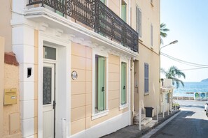 A building with a balcony, a door, and a window with shutters.