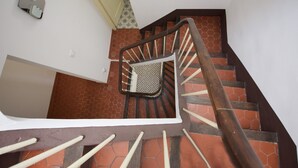 A staircase with a handrail, a patterned floor, and a white wall.