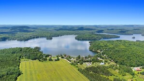 Vista aérea de un lago rodeado de colinas boscosas y un pequeño pueblo con casas y campos.