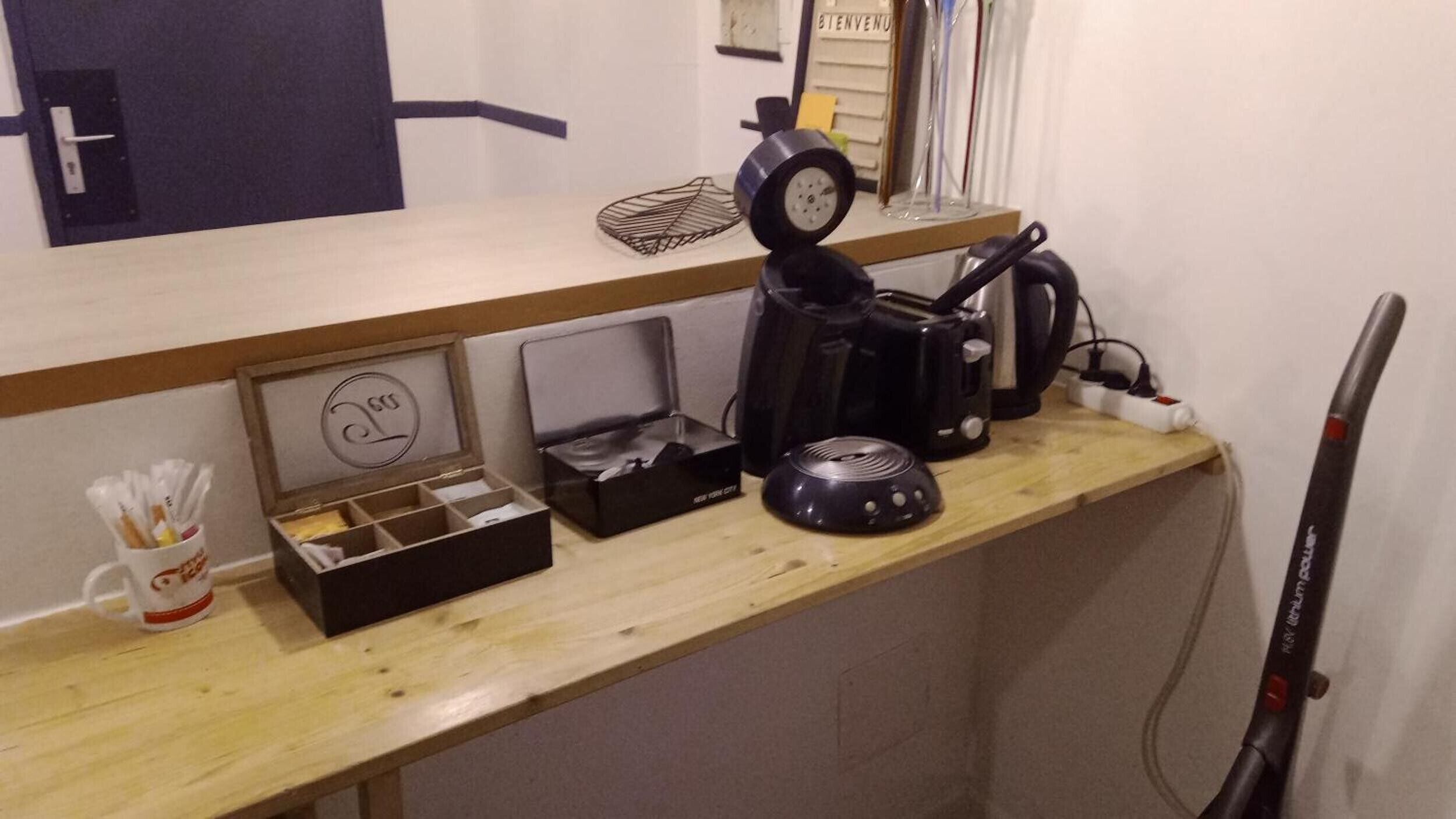 A kitchenette with a coffee maker, toaster, and a clock on the wall.