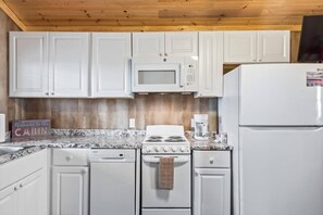 A kitchen with white cabinets, a microwave, a stove, a dishwasher, and a refrigerator.