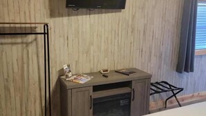 A bedroom with a bed, a wooden desk with a flat-screen TV, and a wardrobe. - Tiny cabin on 10 acres with pond (Albertville)