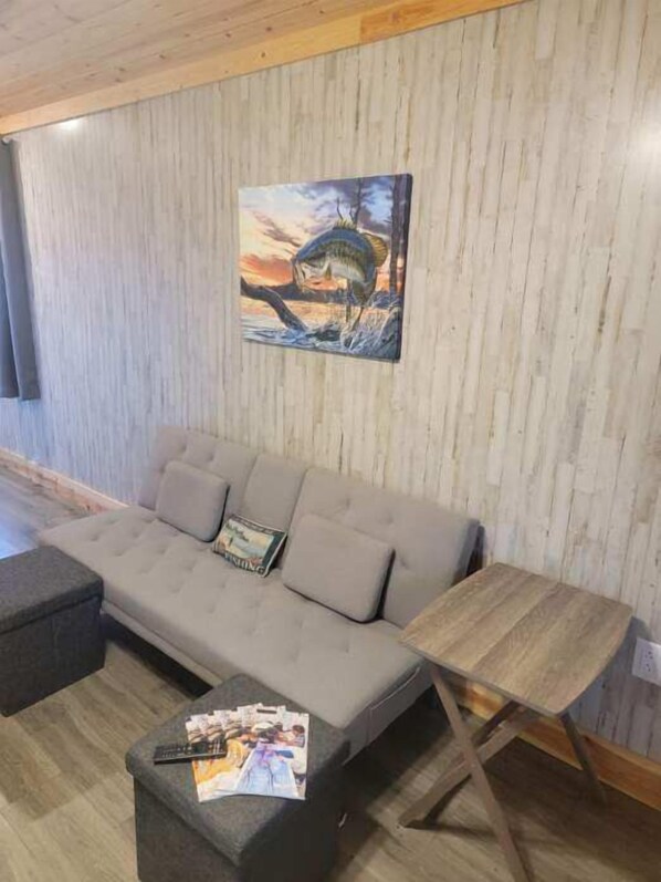 A modern living room with a grey sofa, a wooden coffee table, and a painting of a fish jumping out of water.