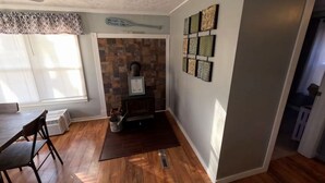 A room with a fireplace, a dining table, and a window with blinds.