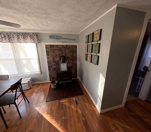 A room with a fireplace, a dining table, and a window with blinds.