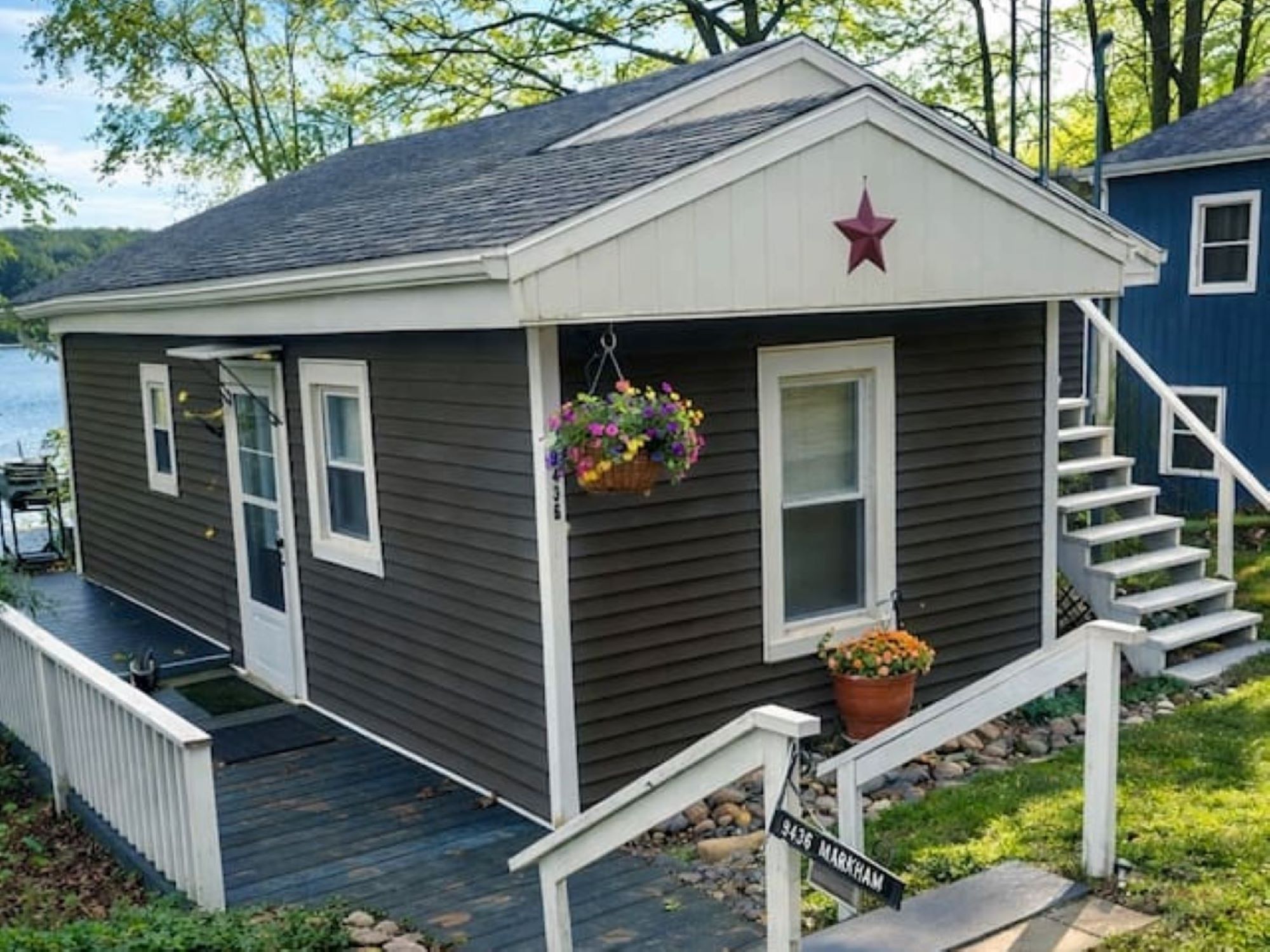 A small house with a porch, a star on the roof, and a flower pot on the steps.
