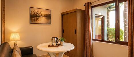 A cozy room with a round table, a sofa, a painting, and a window with curtains.
