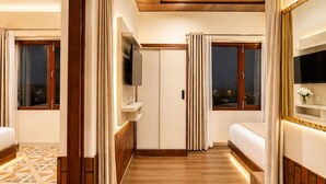 A hotel room with a bed, a TV, a wardrobe, and a window with curtains. - Jungle Nest Retreat Resort (Ramnagar)