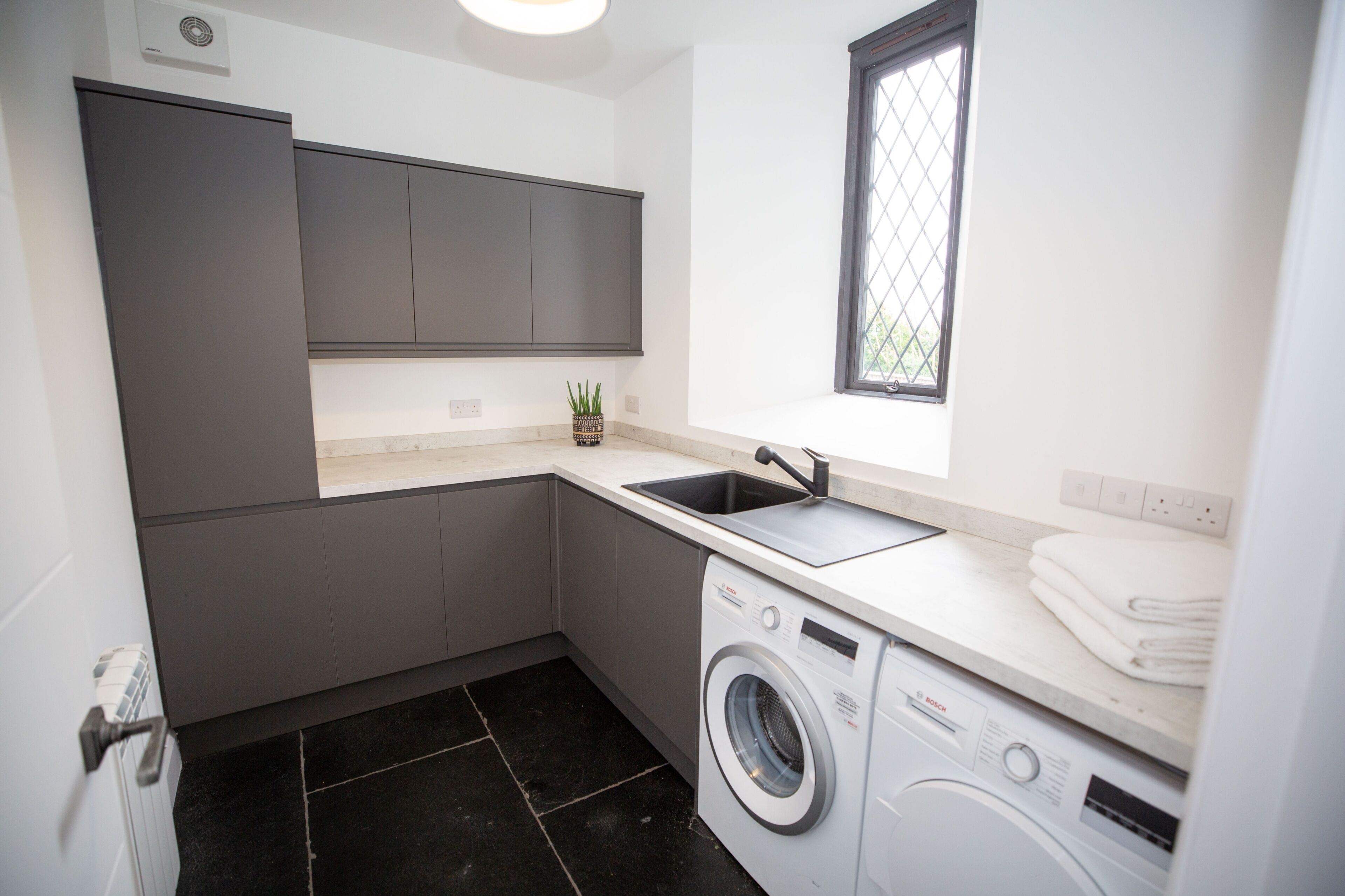 A compact kitchen with a washing machine, a sink, and a window.