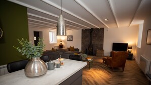 A modern living room with a sofa, a coffee table, and a fireplace. - Stunning 3 Bed Converted Village Hall Near Kelso (Kelso)