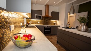 A modern kitchen with a large island, a microwave, oven, and a hanging light fixture. - Stunning 3 Bed Converted Village Hall Near Kelso (Kelso)