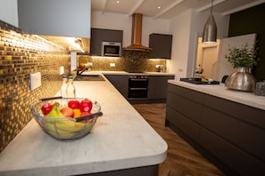 A modern kitchen with a white countertop, a stainless steel oven, and a copper range hood. - Stunning 3 Bed Converted Village Hall Near Kelso (Kelso)