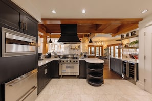 A modern kitchen with stainless steel appliances, a central island, and a bar area. - Premier Mountain Village Condo by InvitedHome | Hot Tub, Gym, Balcony Views (Telluride)