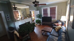 Ein Wohnzimmer mit Kamin, einer Couch, einem Fernseher und einem Deckenventilator.