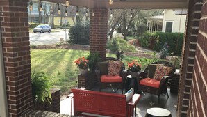 Eine überdachte Terrasse mit Backsteinmauern, Gartenmöbeln und Lichterketten.
