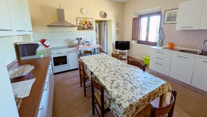 Una cucina compatta con angolo ristoro, fornello, lavello e televisore.