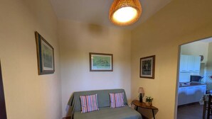 Una camera accogliente con un letto, un tavolino con una lampada e quadri appesi alle pareti.