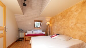 Ein Schlafzimmer mit Holzbalkendecke, einem Bett mit weißer Bettwäsche, einem roten Sofa, einem Fenster und einer Lampe.