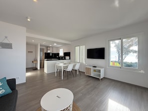 A modern living room with a dining area, a kitchen, and a TV mounted on the wall. - Agi Residencial Roses 215 Apartamento for rent in Roses Girona. (Roses)