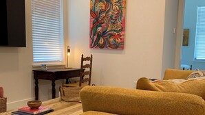 A living room with a sofa, a table with a bowl, a painting on the wall, and a TV mounted on the wall. - Beautiful New Construction 2 - Bedroom / 2 Bath located in West University. (Austin)