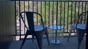 A balcony with two chairs and a small table, overlooking a street and trees. - Beautiful New Construction 2 - Bedroom / 2 Bath located in West University. (Austin)