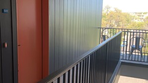 A modern building with a red door, a balcony with a metal railing, and a view of the outside. - Beautiful New Construction 2 - Bedroom / 2 Bath located in West University. (Austin)