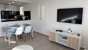 Uma sala de estar moderna com área de refeições, TV fixada na parede e um armário minimalista.