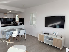 A modern living room with a dining area, a TV mounted on the wall, and a minimalist cabinet. - Agi Residencial Roses 201 Apartamento for rent in Roses Girona. (Roses)