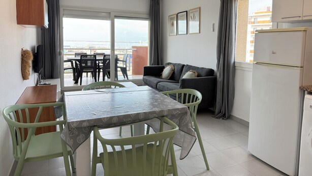 Un espace de vie compact comprenant un coin repas, un canapé, un ventilateur de plafond et une vue sur la mer.