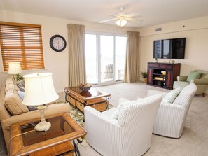 A living room with a sofa, armchairs, a coffee table, a television, and a ceiling fan. - Balconies with stunning views from Master Bedroom, Living Room and 2nd Guest (Miramar Beach)