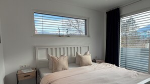 A bedroom with a bed, a nightstand, a window, and a view of the outdoors. - Inntal Alpin Apartments -quiet terrace with mountain views (Telfs)