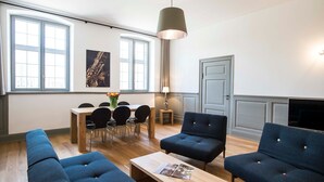 Ett modernt vardagsrum med en matplats, stora fönster, en soffa och en tv.