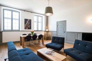 Un salon moderne comprenant un coin repas, de grandes fenêtres, un canapé et un téléviseur.