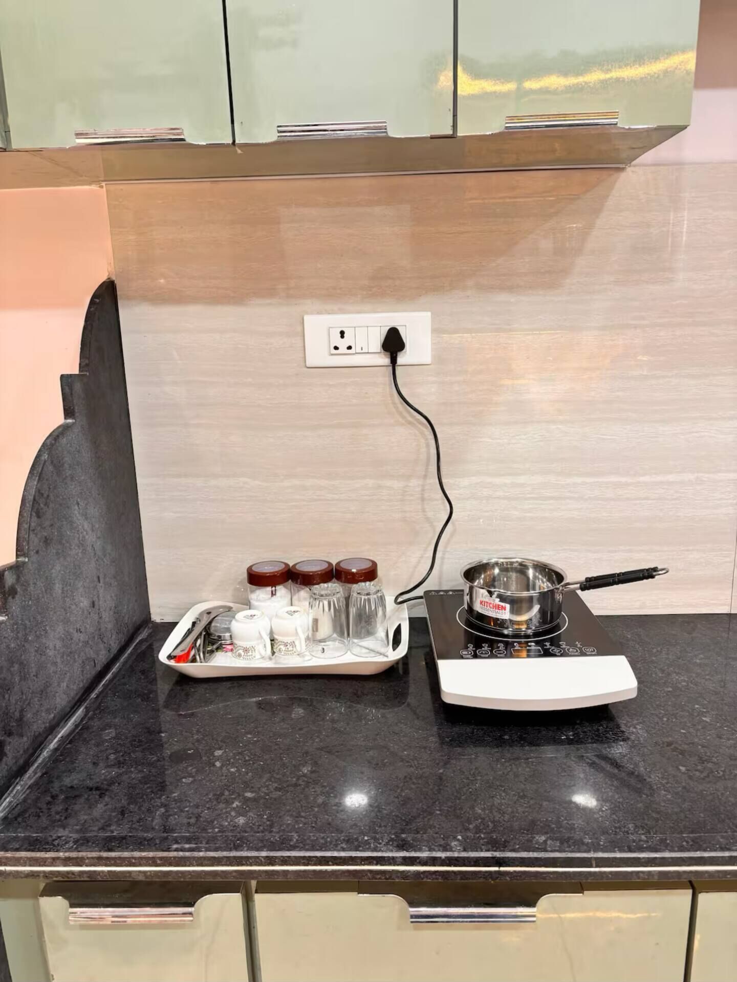 A kitchen counter with a kettle, a tray with condiments, and a portable induction cooktop.