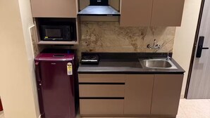 Una cocina compacta con microondas, un refrigerador pequeño, estufa y lavamanos.