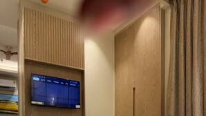 Una habitación de hotel con una cama, un televisor montado en un panel de madera y un armario.