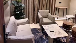 Una sala de estar con sofá, sillón, mesa de centro y una mesita.