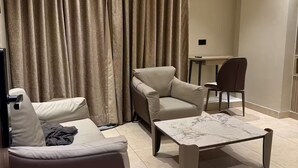 Una sala de estar con un sofá, dos sillones, una mesa de centro y un televisor.