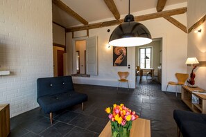 Un salon moderne avec un canapé, une table basse agrémentée de fleurs et, au fond, un coin repas.