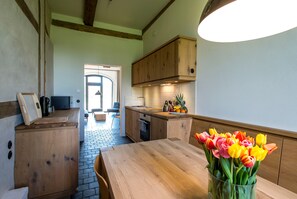 Une cuisine avec des meubles de rangement en bois, une table à manger et un vase de tulipes.