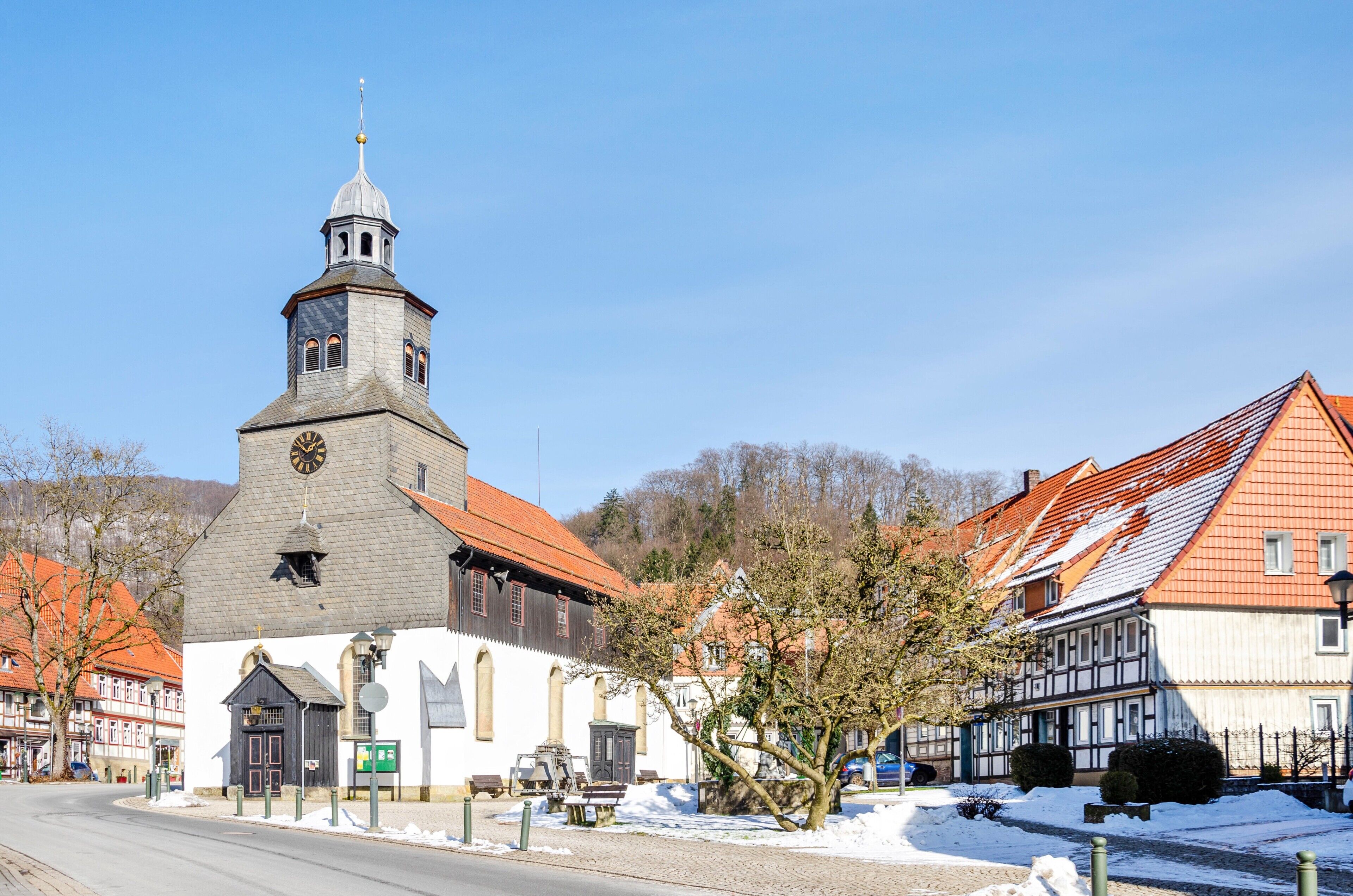 A church with a clock tower, adjacent traditional buildings, and a snow-covered street.